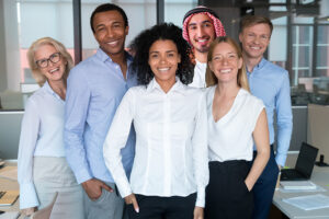 Smiling young mixed race female leader standing looking at camera with diverse team people, happy african american employee business coach millennial professional with office workers group portrait